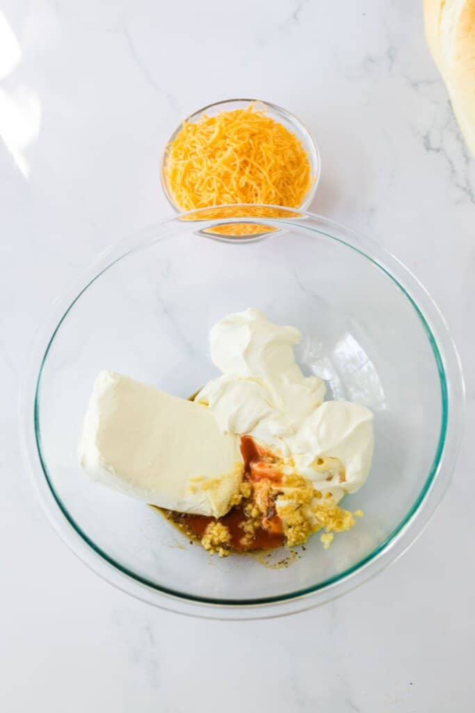 cream cheese, sour cream, and seasonings being mixed in a glass bowl.