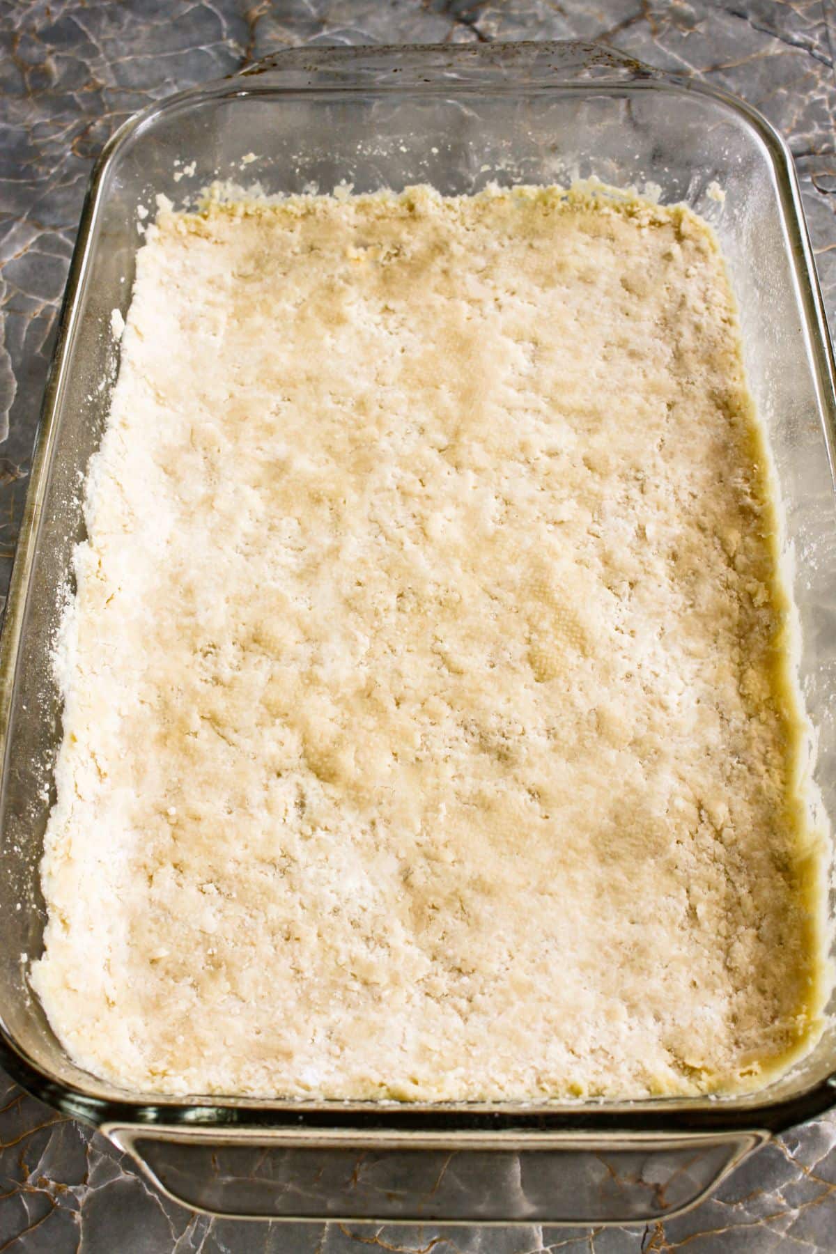crust being pressed into a glass baking dish.