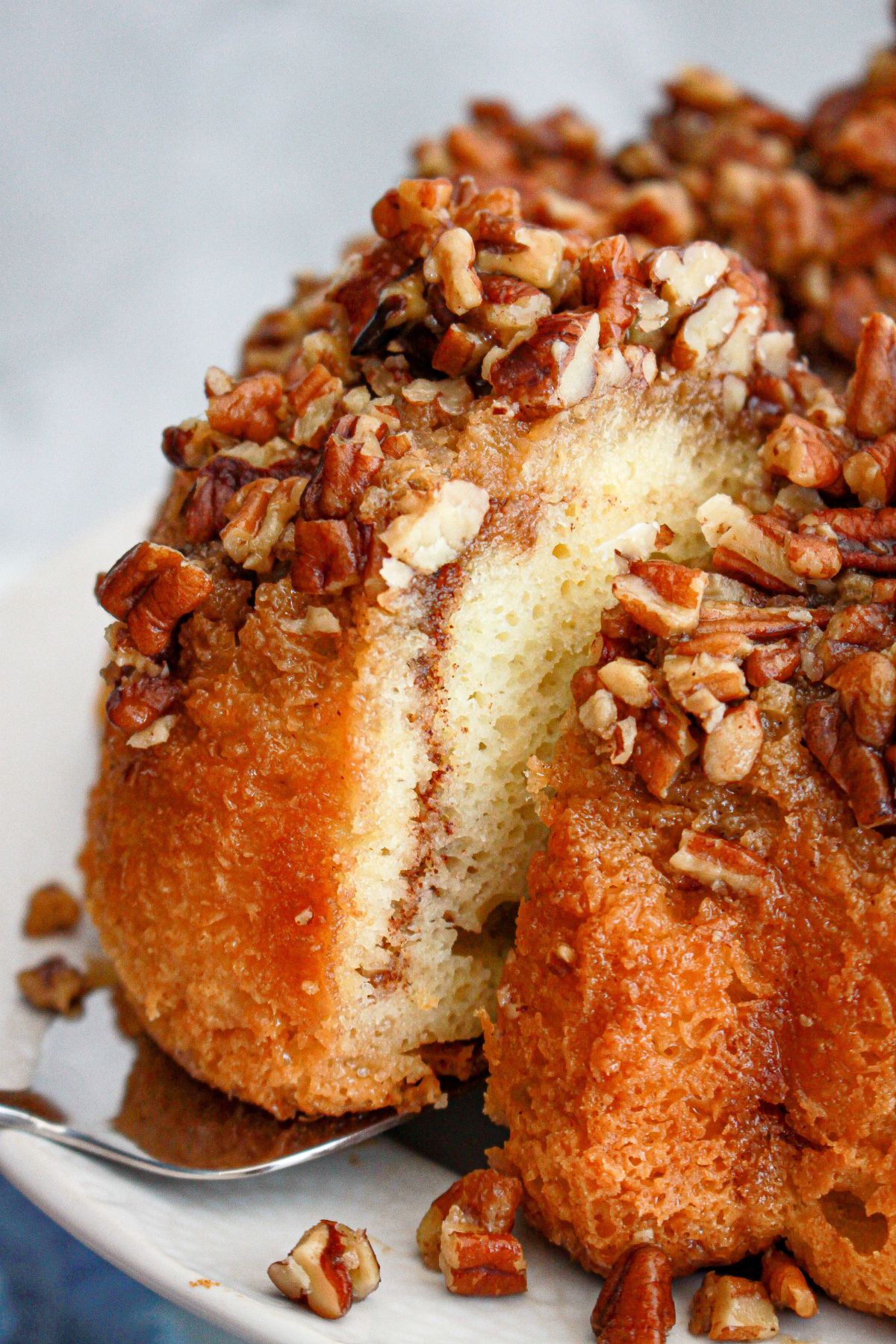 slice of pecan upside down cake being removed from the pan.