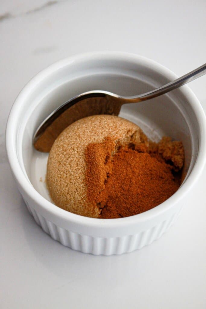 cinnamon and brown sugar being mixed together in a small bowl.