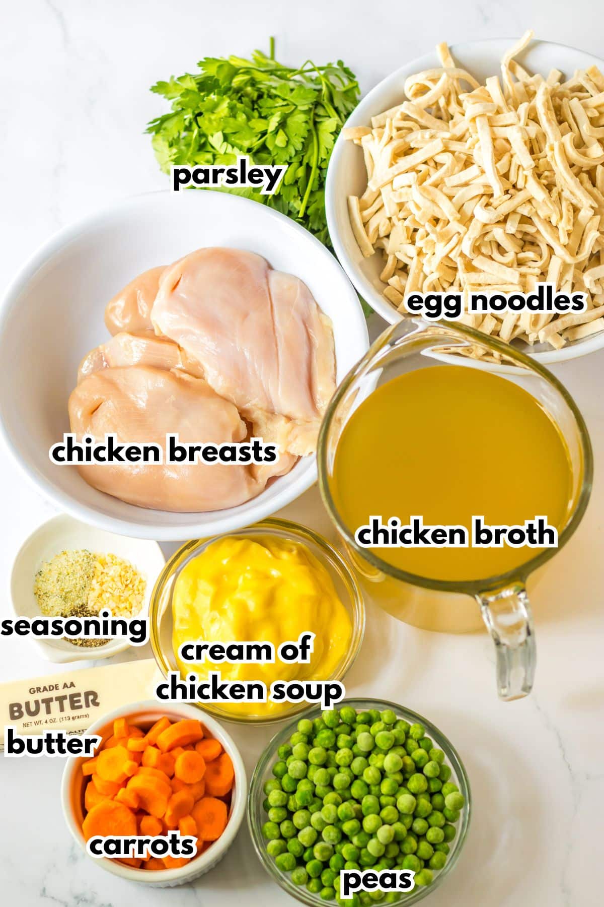 bowls of chicken breasts, egg noodles, seasoning, cream of chicken soup, butter, carrots, peas, and parsley.
