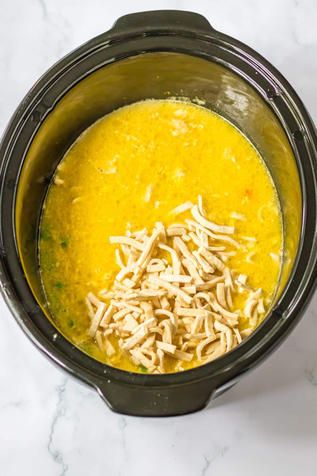 frozen egg noodles being added to the crockpot.