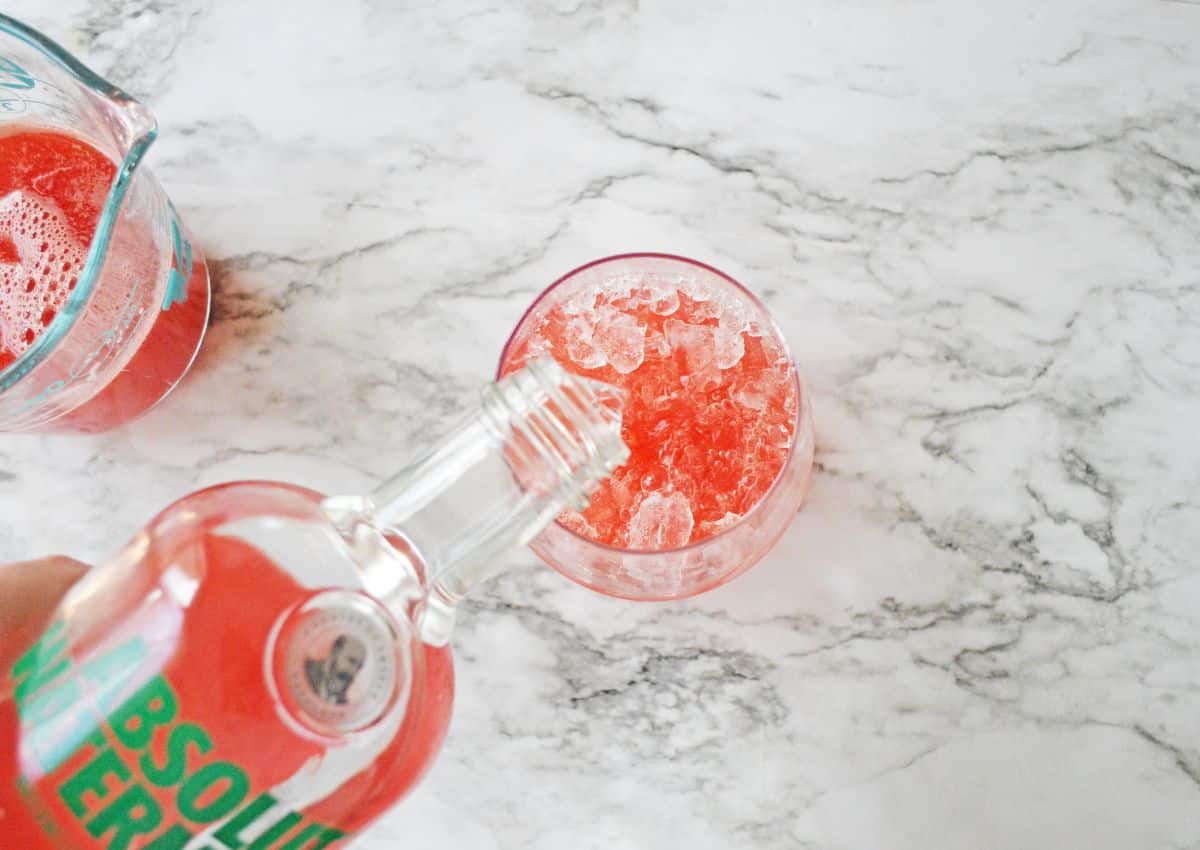 vodka being poured into a glass filled with ice.
