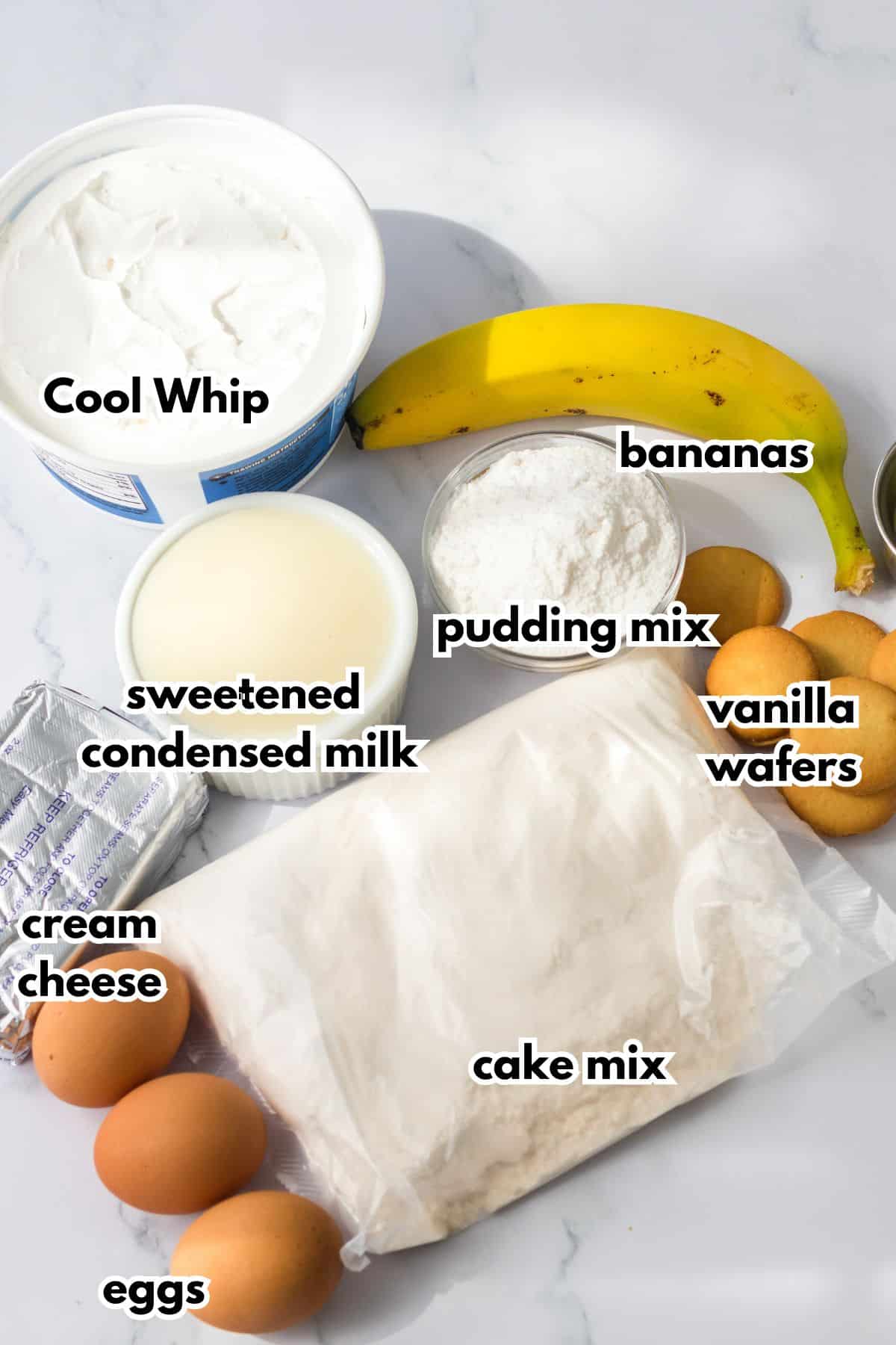bowls of cool whip, condensed milk, pudding mix, bananas, cream cheese, eggs, cake mix, and vanilla wafers on a counter.