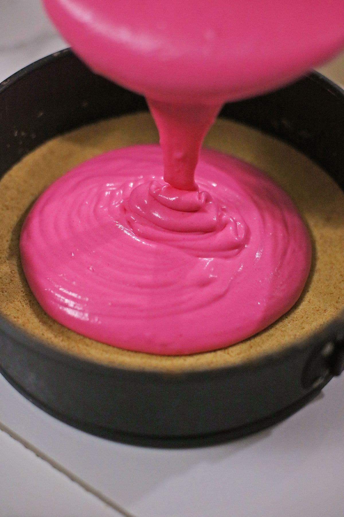 cheesecake batter being poured onto a sugar cookie crust.