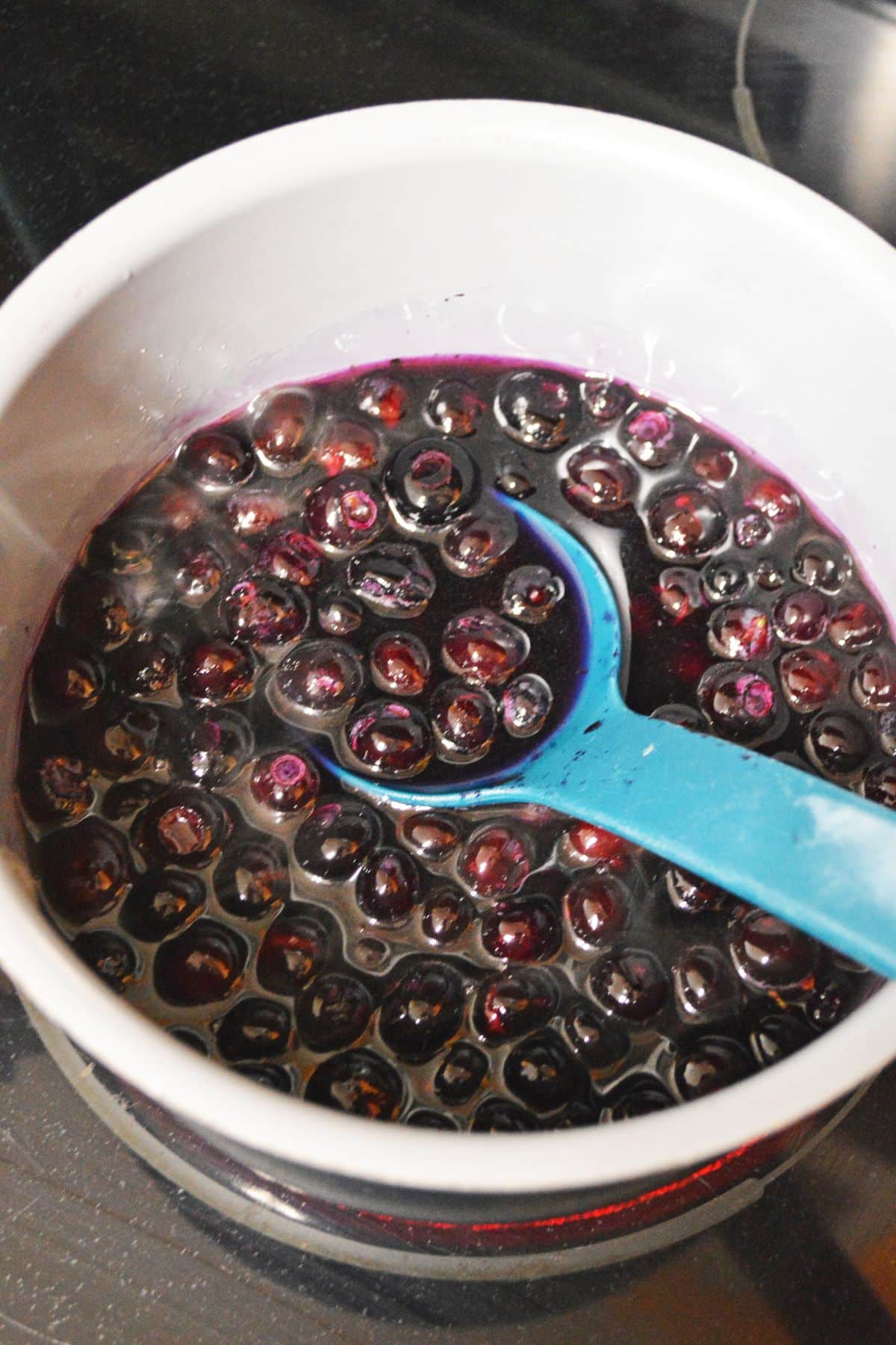 blueberry syrup being cooked in a saucepan.