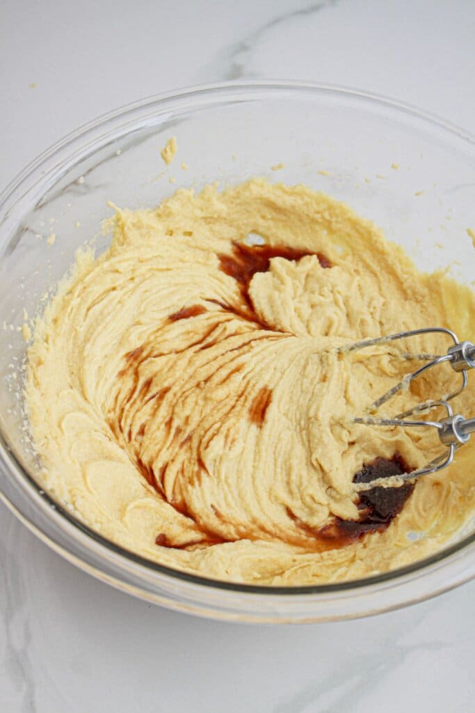 vanilla extract being added to batter in a large glass bowl.