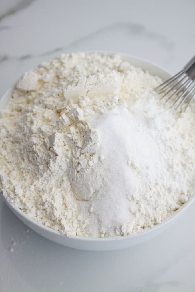 flour, sugar, salt, and baking powder being mixed in a medium bowl.