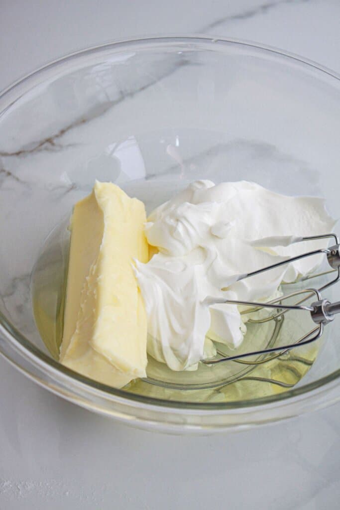 butter, sour cream, and oil being mixed in a large glass mixing bowl.