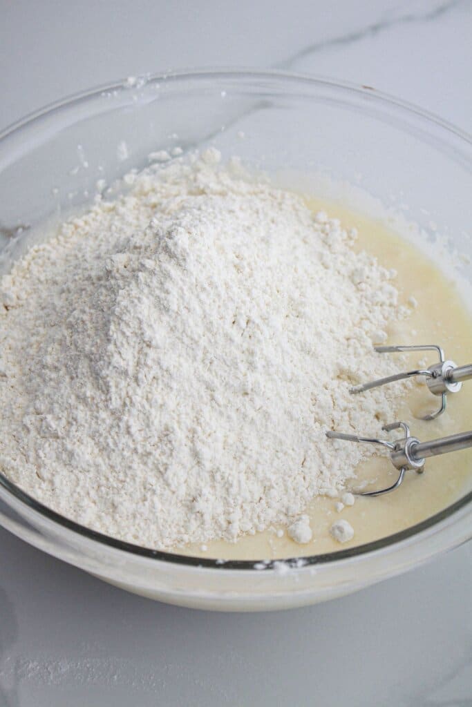 dough being mixed in a glass mixing bowl.