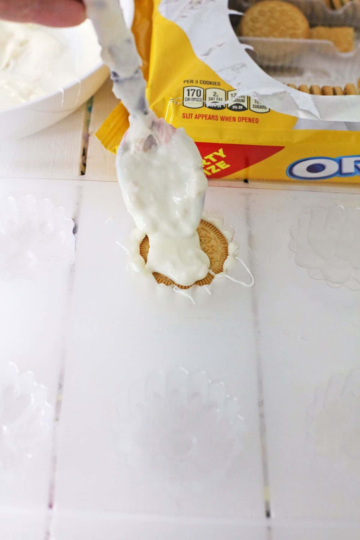 white chocolate being spread on top of a cookie.