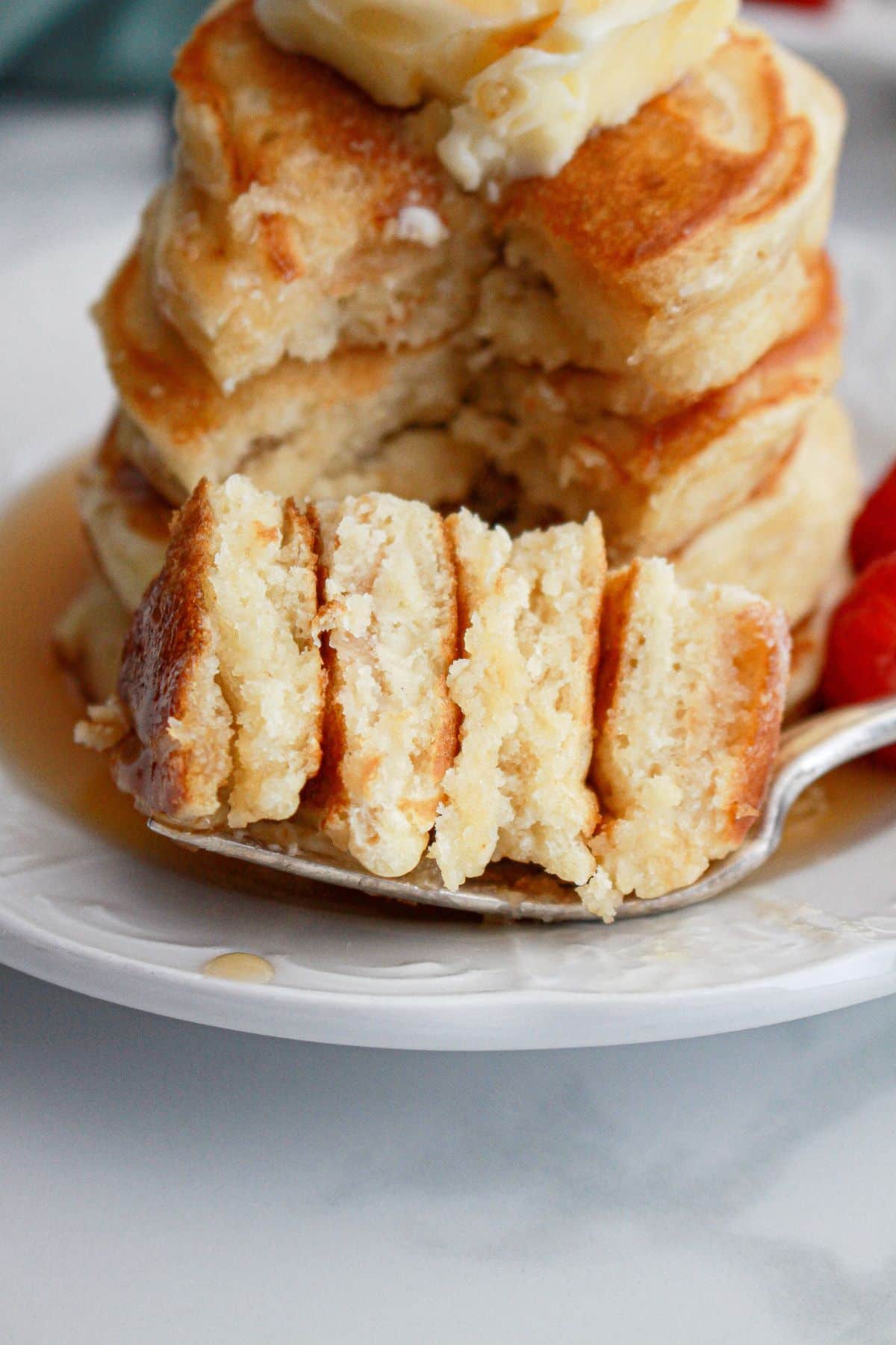 bite of fluffy pancakes on a plate.