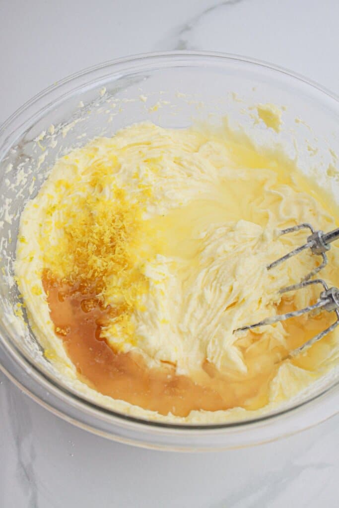 butter, sugar, vanilla, and lemon zest being combined in a large glass bowl.