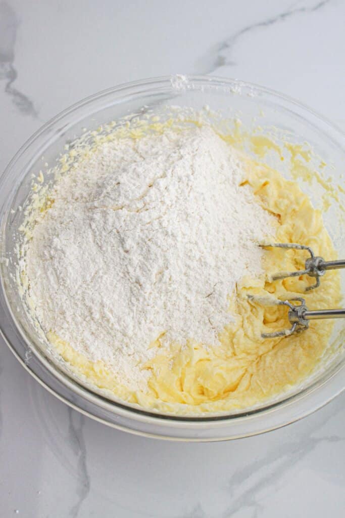 dry ingredients being added to wet ingredients in a large glass bowl.