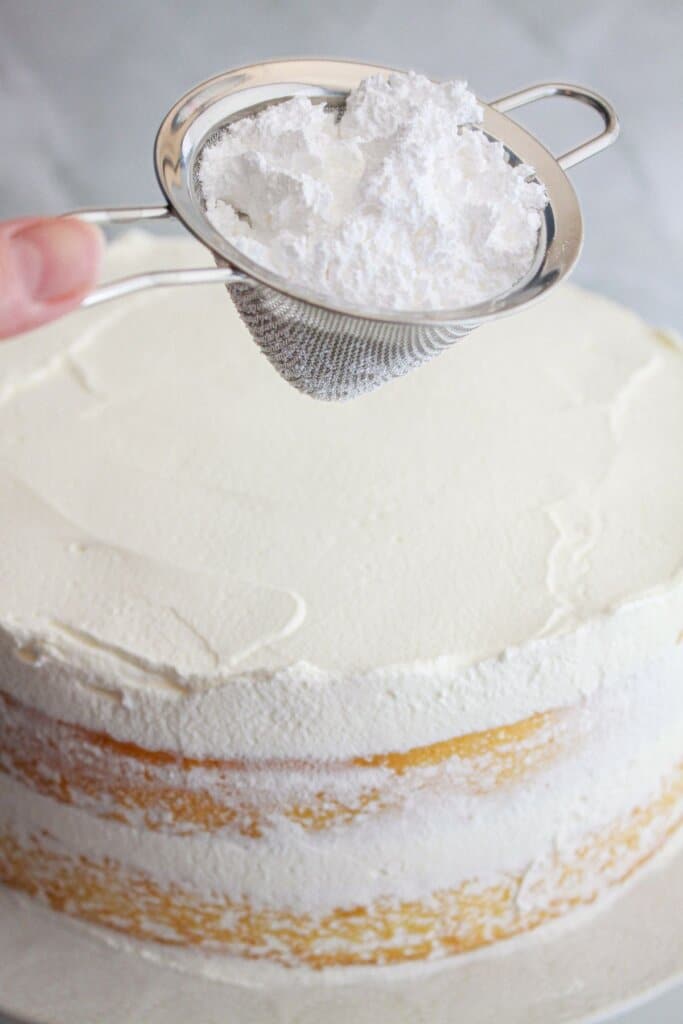 powdered sugar being sprinkled on a top of a cake.