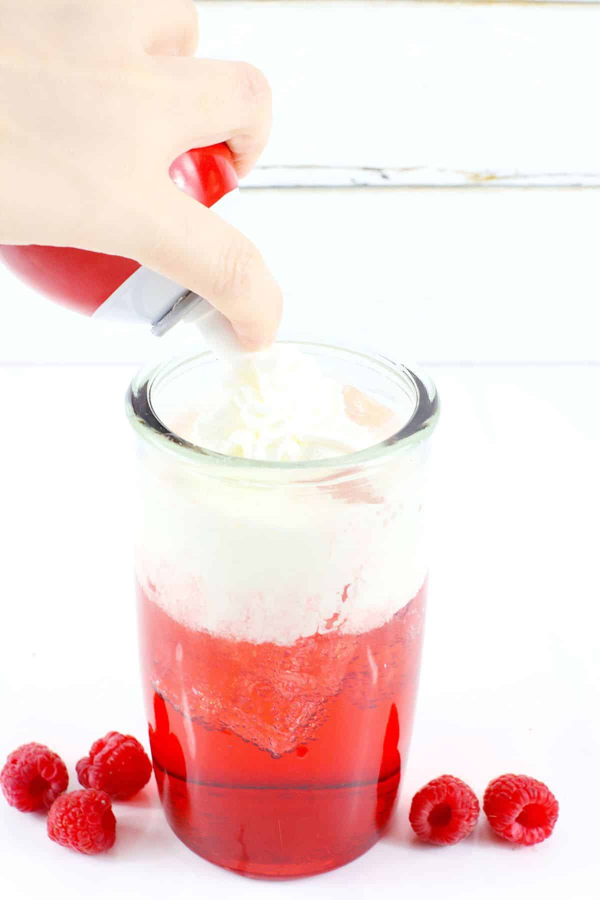 whipped cream being added to a the top of a drink.