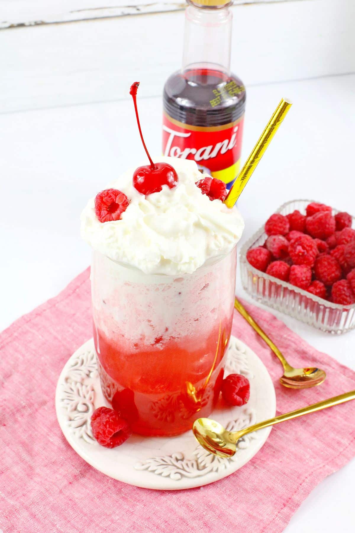glass of raspberry cocktail on a small plate.