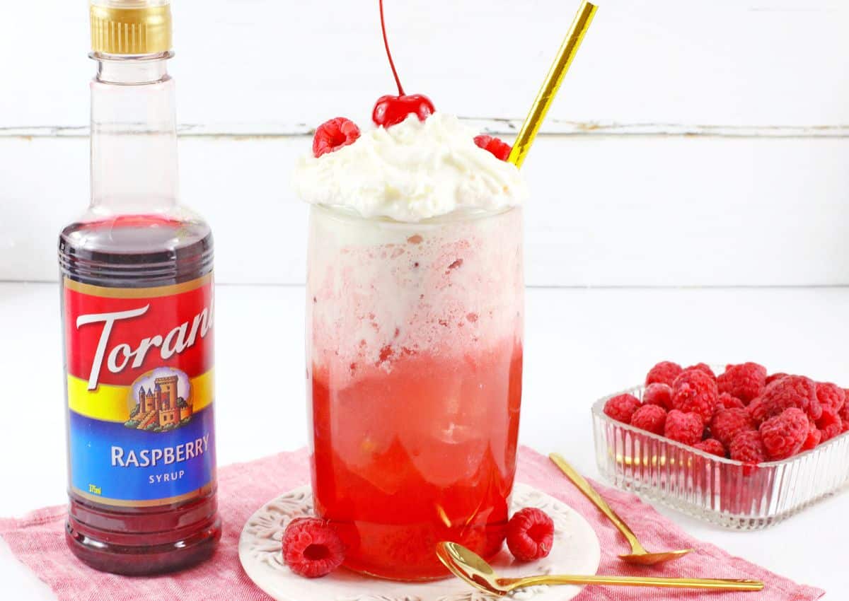 glass of raspberry cocktail on a small plate.