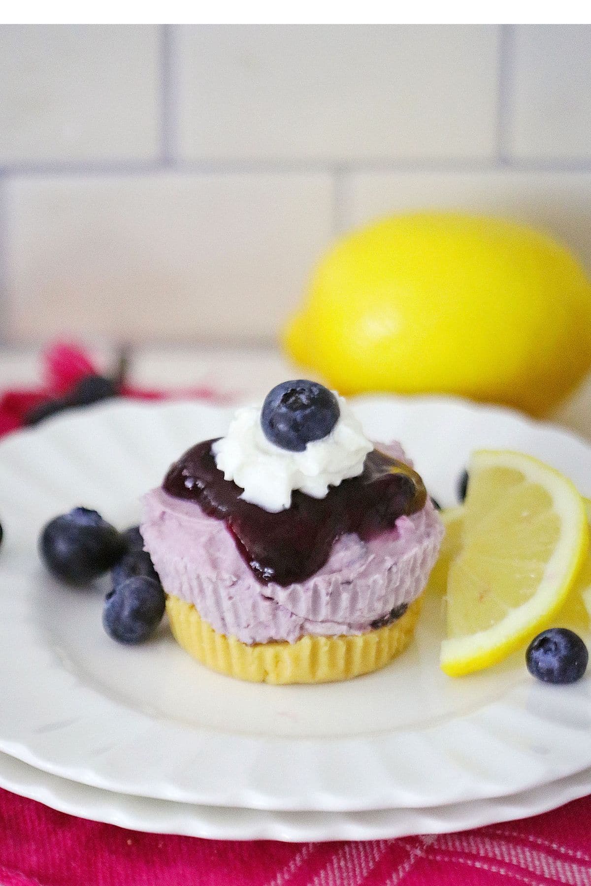 mini blueberry lemon cheesecake on a small plate with lemon slices and fresh blueberries.