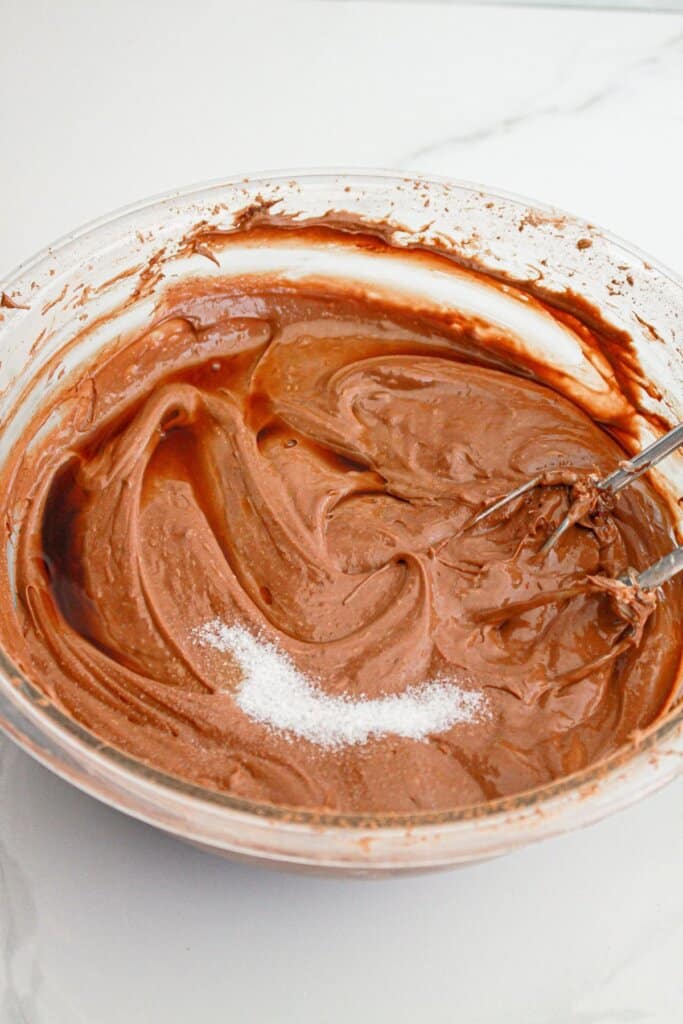 cream cheese, vanilla, salt, and sugar being mixed in a large bowl.