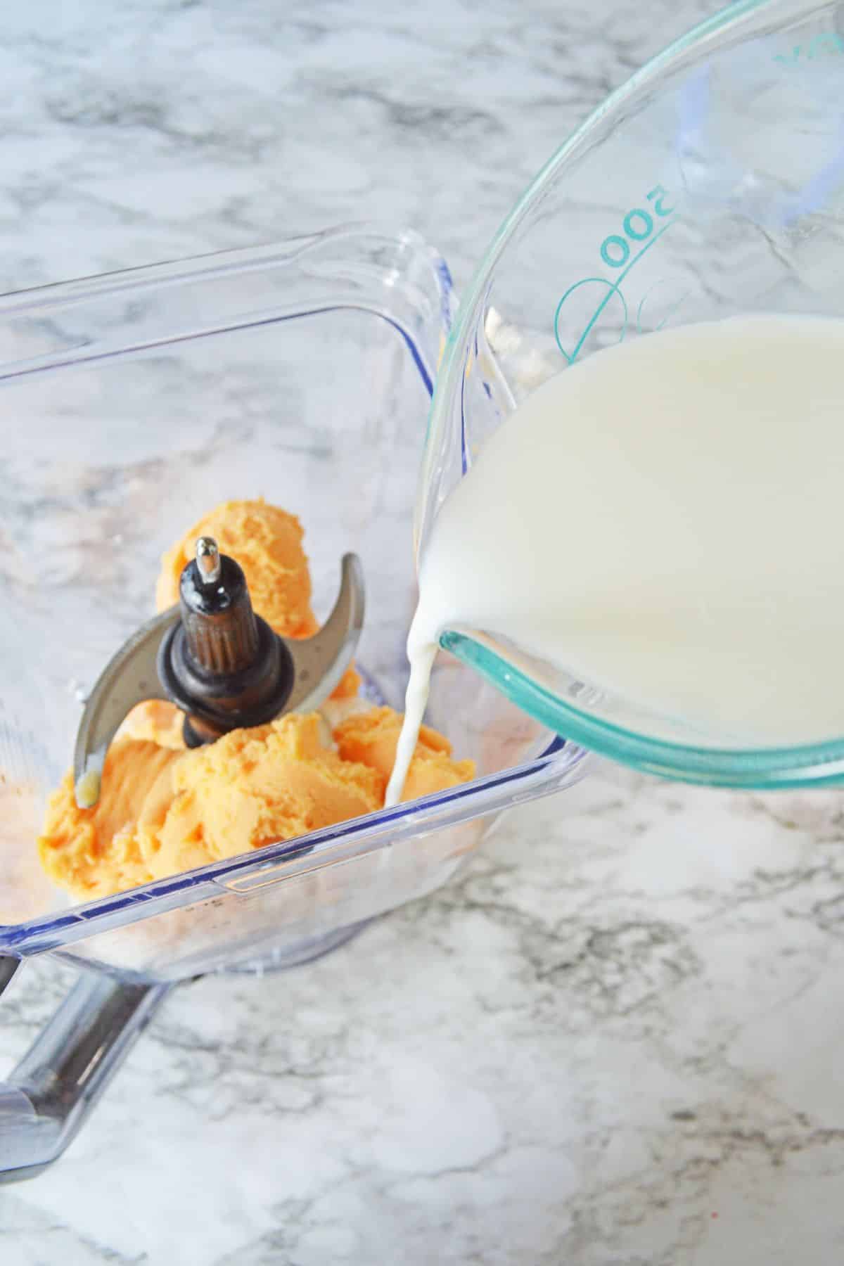 sherbet and milk being added to a blender.