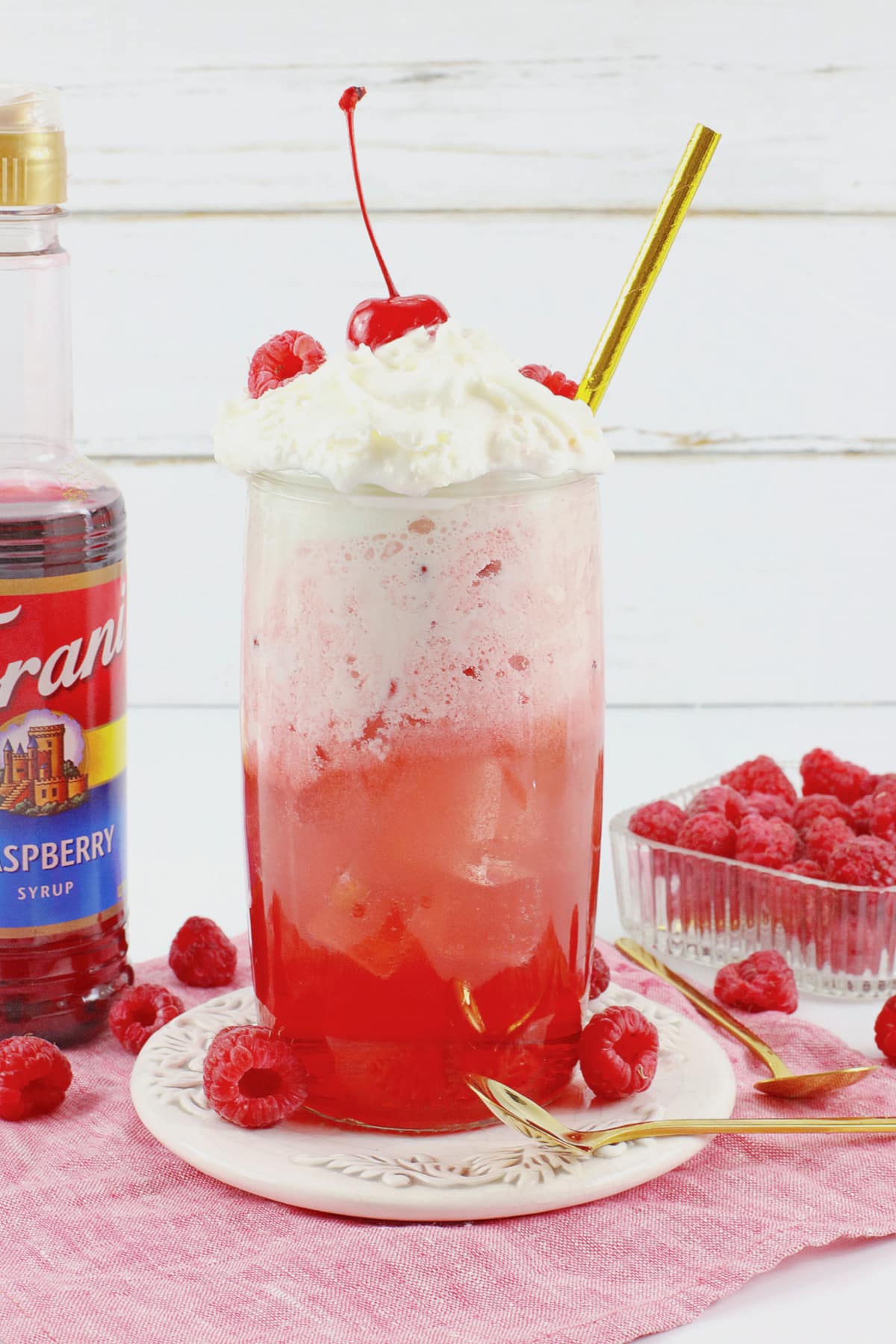 glass of raspberry cocktail on a small plate.