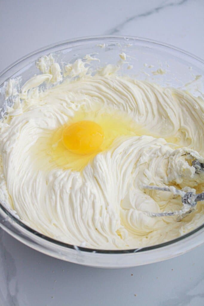 eggs being added to batter in a glass mixing bowl.