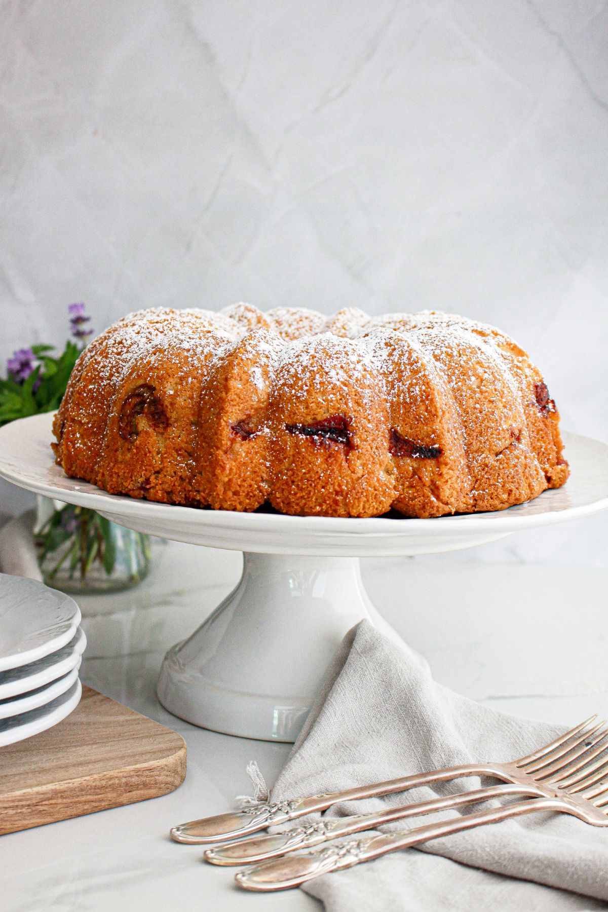 uncut rhubarb strawberry bundt cake on a cake platter.
