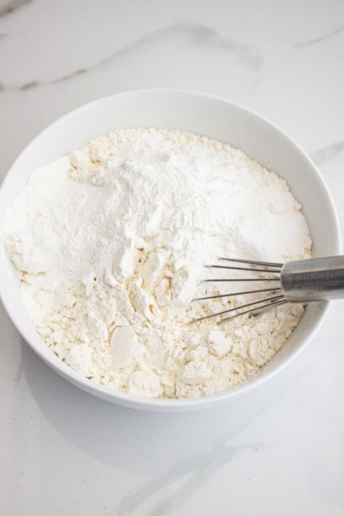 flour, salt, and baking powder being mixed together in a small bowl.
