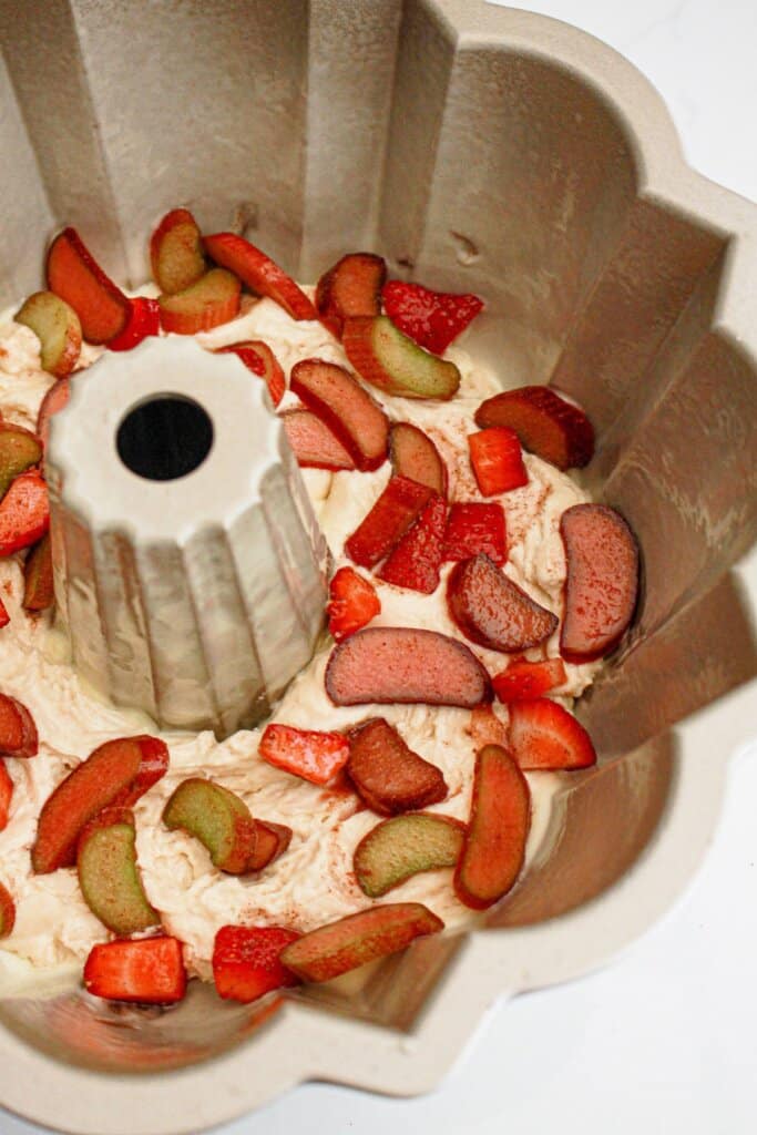 layers of fruit and batter being added to a baking dish.