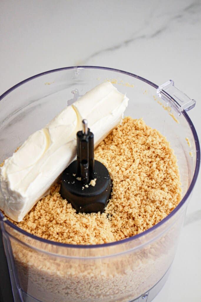 Golden Oreo's and cream cheese being mixed in a food processor.