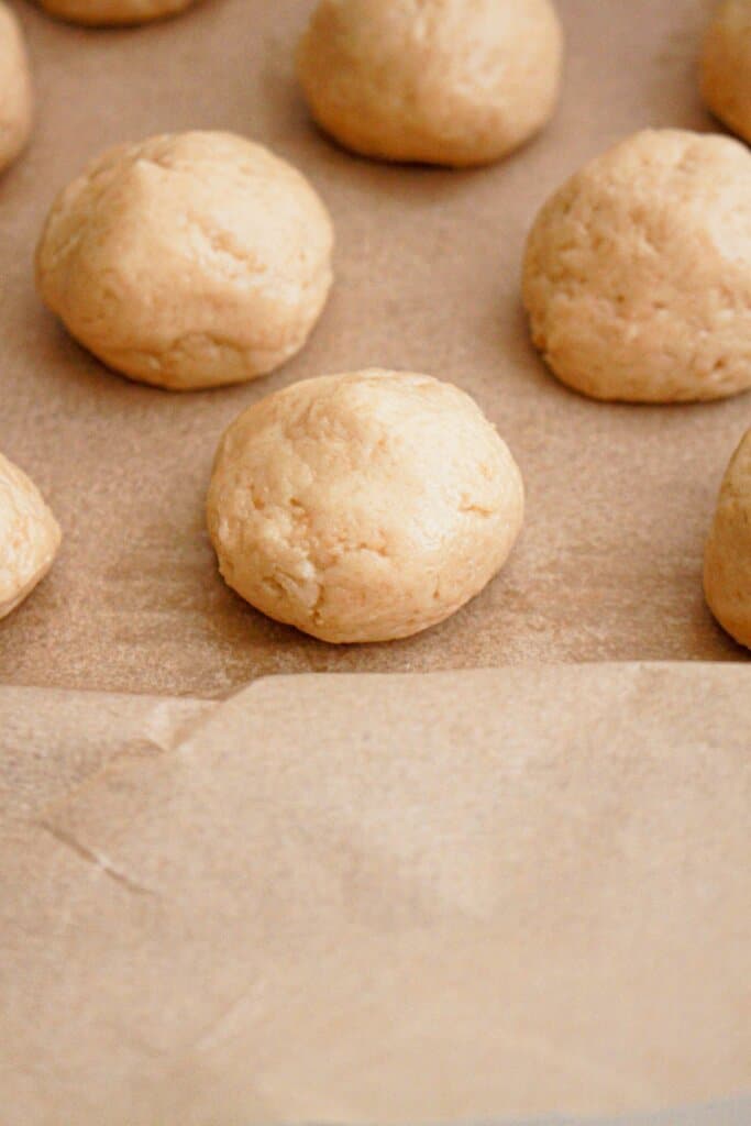 cookie dough balls on a parchment lined baking sheet.