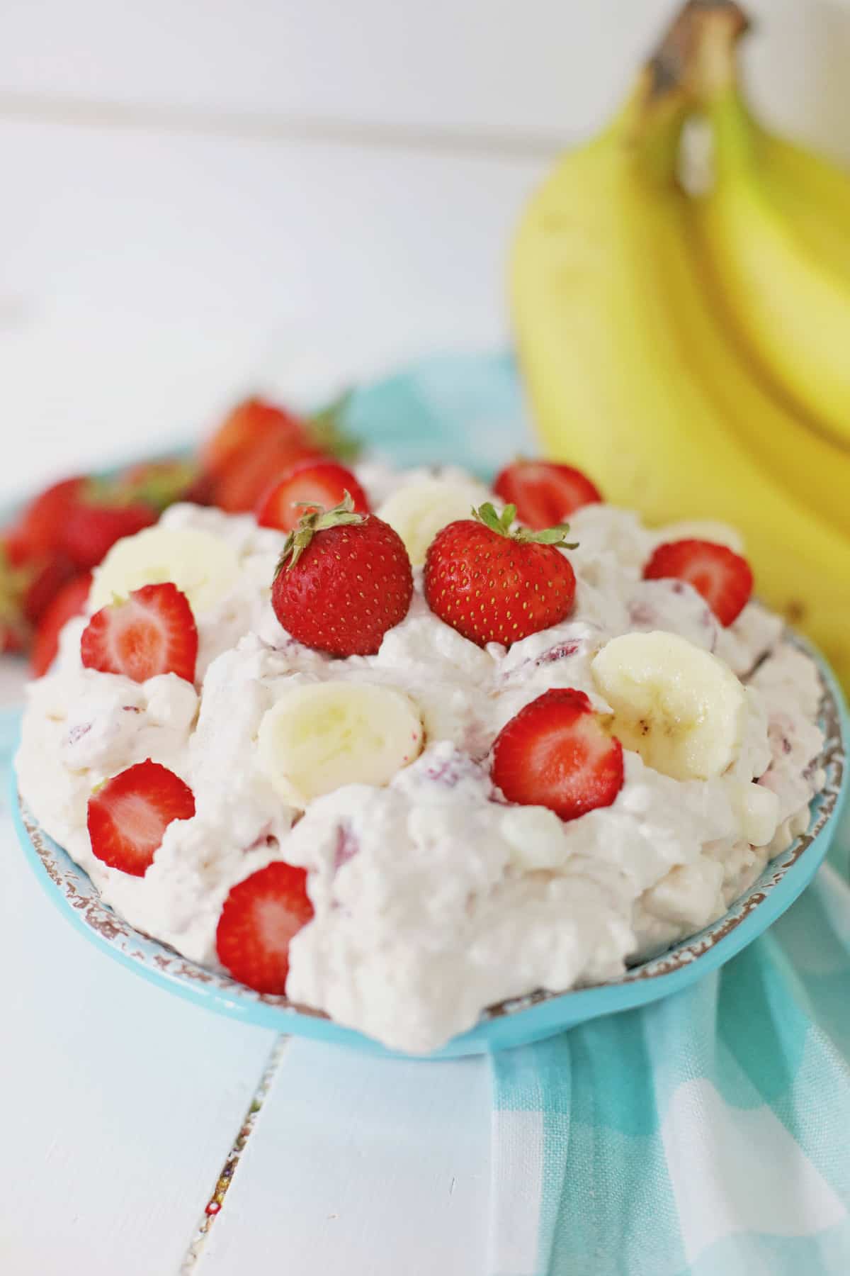 bowl full of strawberry banana cheesecake salad and topped with sliced strawberries.