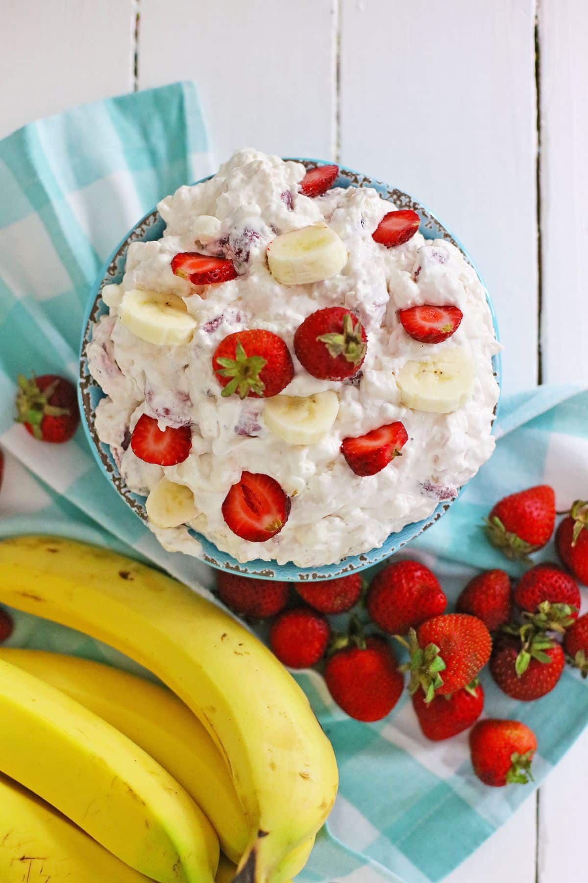 bowl full of strawberry banana cheesecake salad and topped with sliced strawberries.