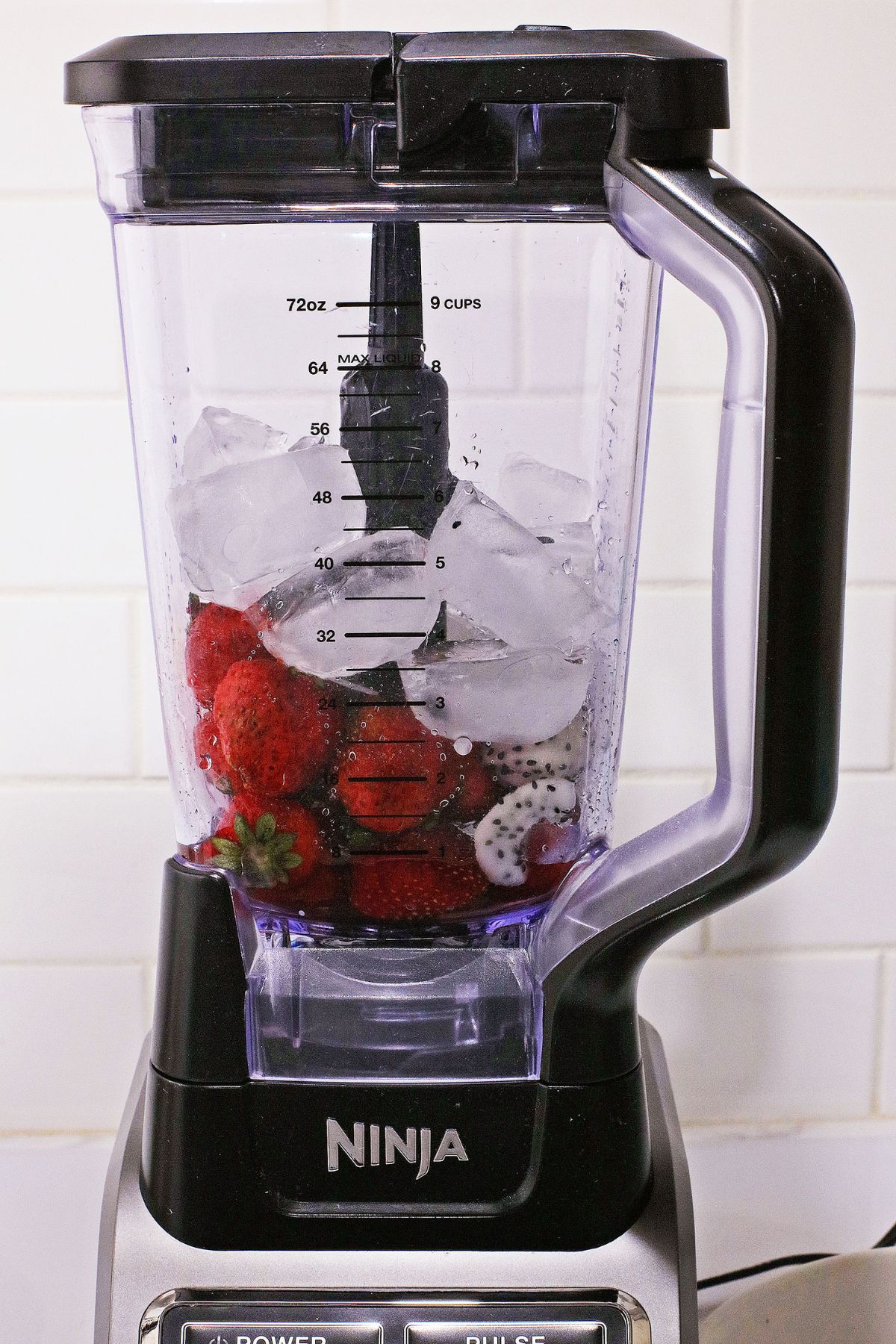 ice, strawberries, and dragon fruit in a ninja blender.