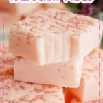 pieces of white chocolate raspberry fudge stacked in a pyramid the top piece has a bite missing.