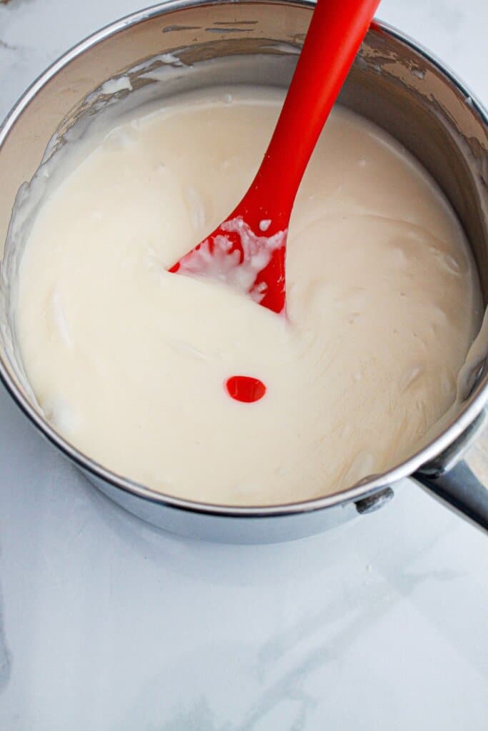 food coloring being added to melted candy in a saucepan.