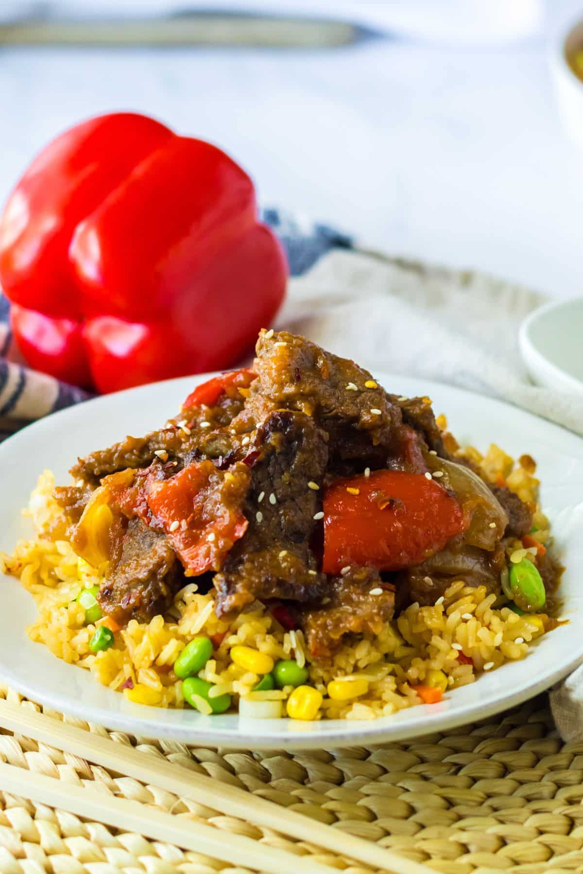 plate full of rice topped with beijing beef.