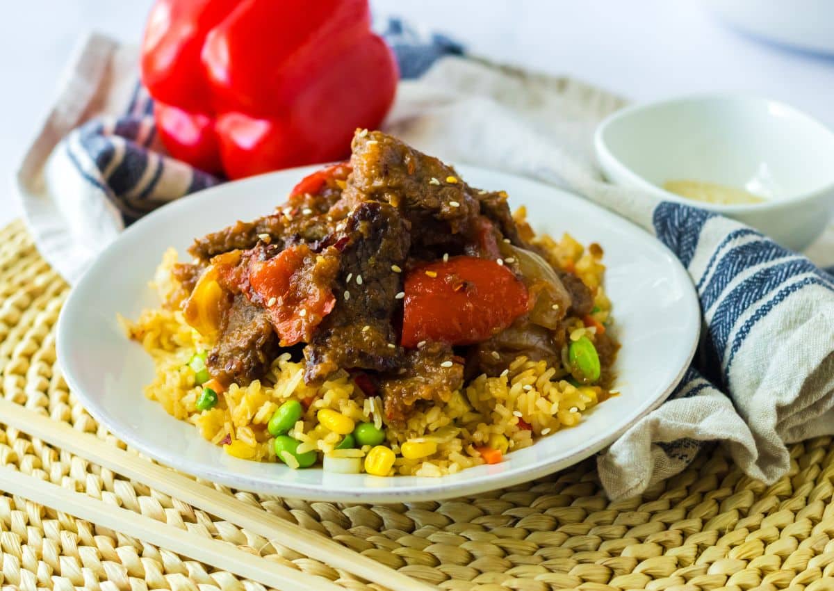 plate full of rice topped with beijing beef.