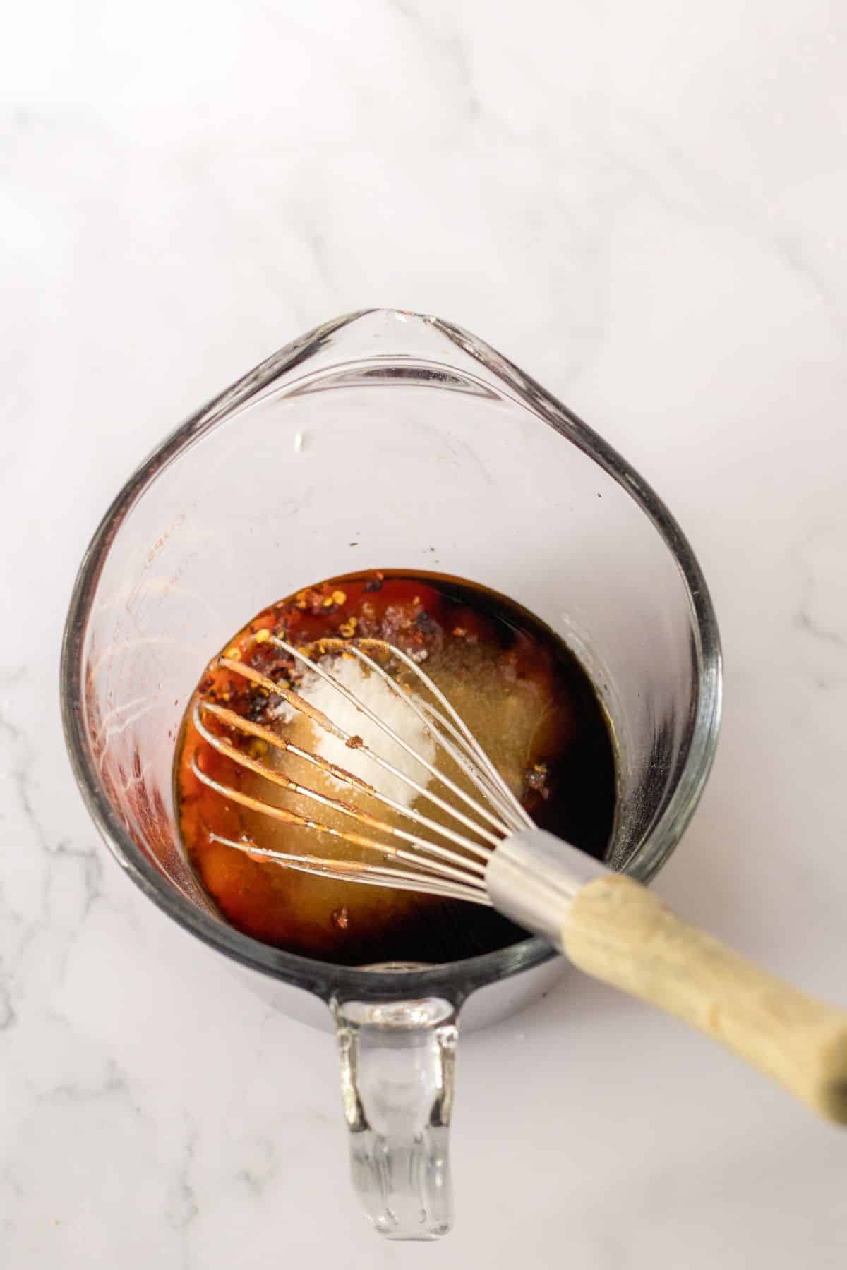 sauce being whisk in a small glass measuring cup.