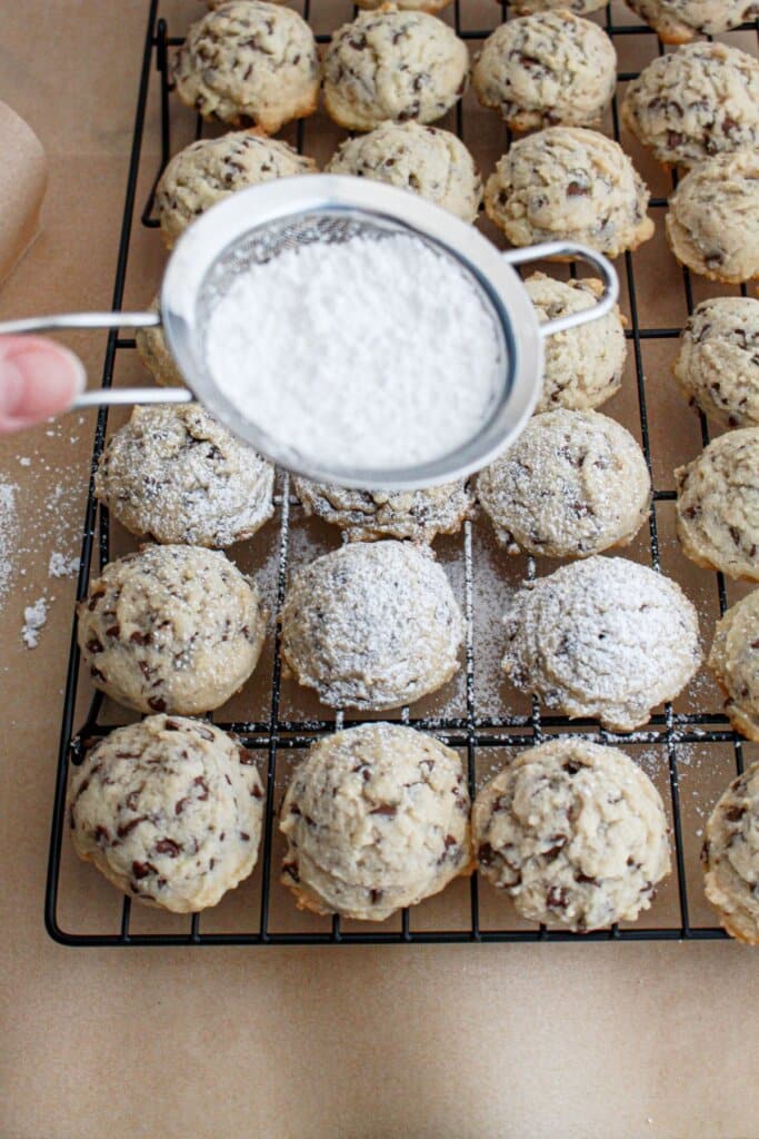 powered sugar being dusted on top of the dessert on a cooling rack.