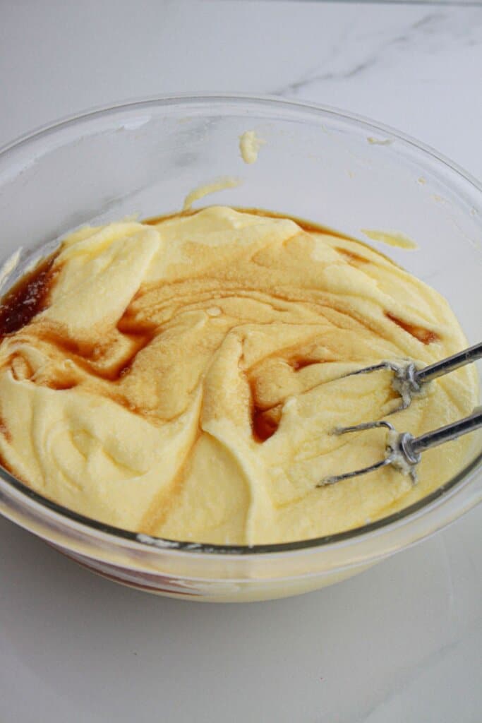 butter, sugar, vanilla, and eggs mixed in a glass bowl.