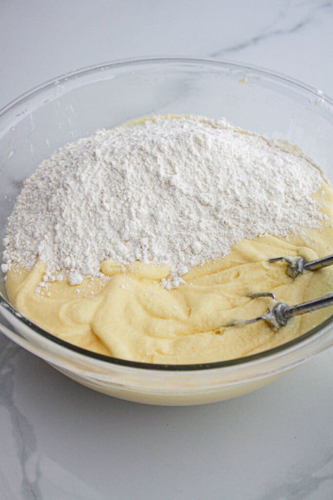 pound cake batter being mixed in a large glass bowl.