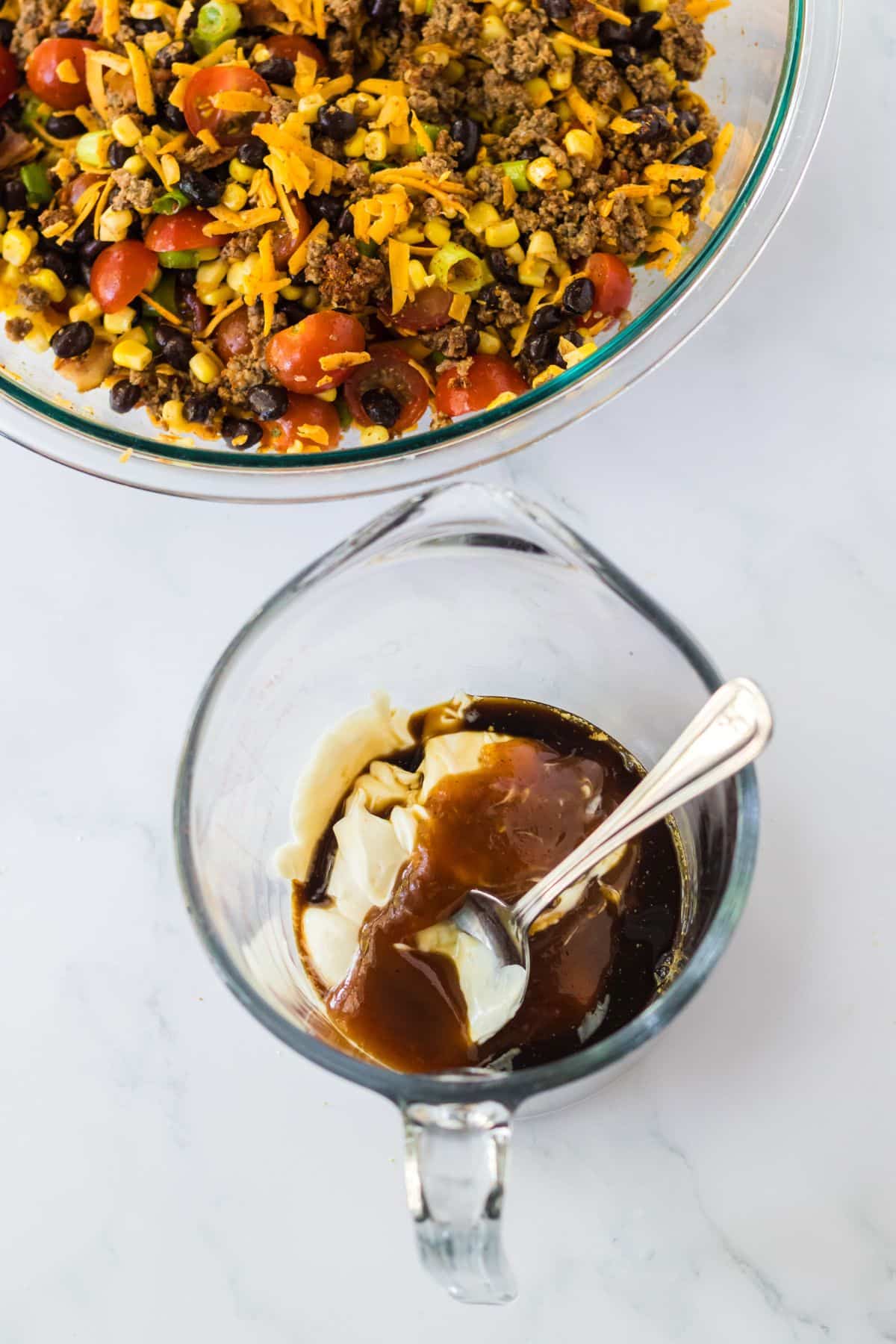 dressing being mixed in a glass measuring cup with a spoon.
