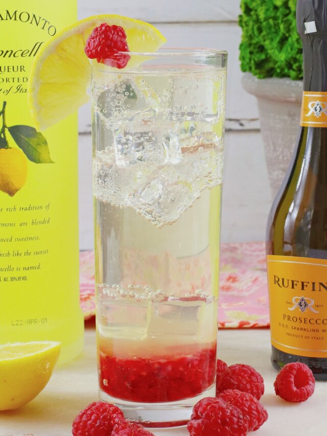 glass of limonello prosecco on a wooden cutting board topped with a slice of lemon.