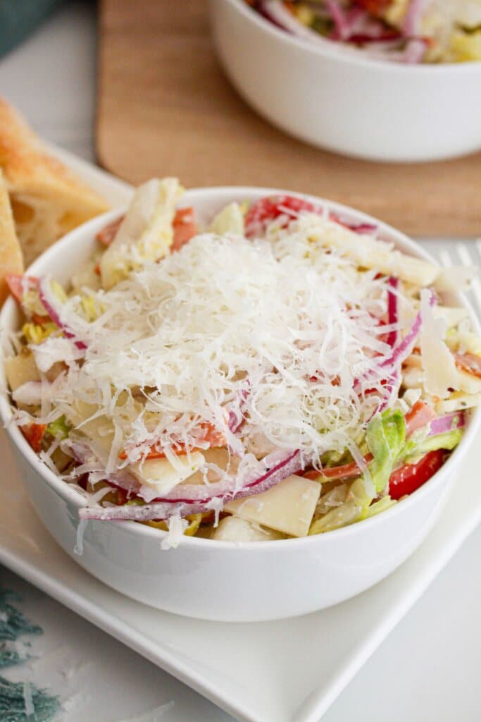 sub salad in a bowl being topped with grated parmesan cheese.