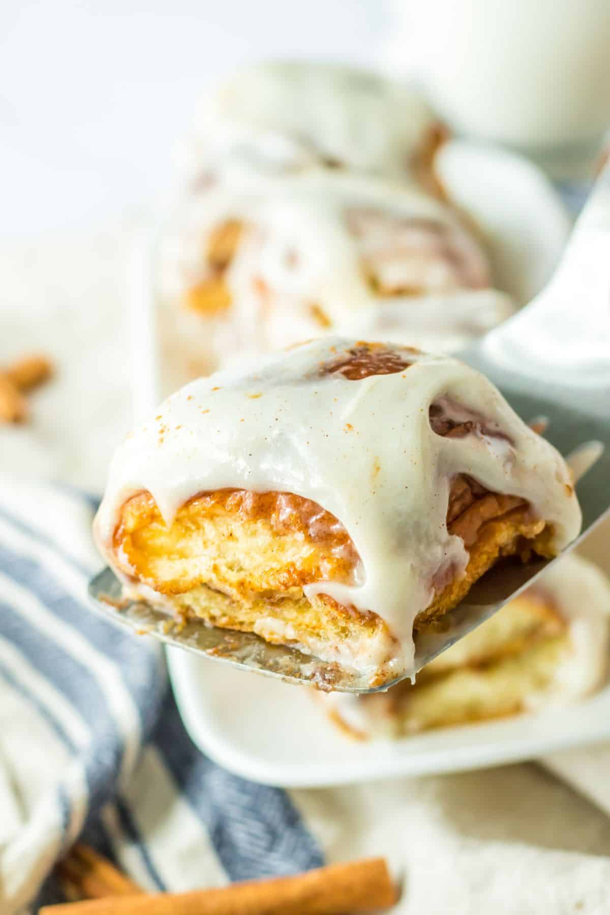 hawaiian cinnamon roll held in the air on a spatula.