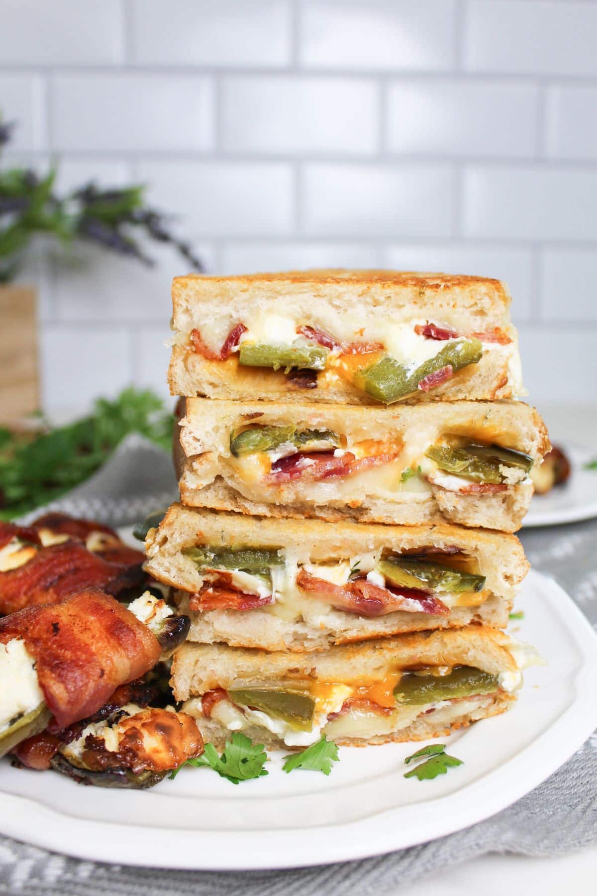 four halves of jalapeno popper grilled cheese sandwiches on a plate.