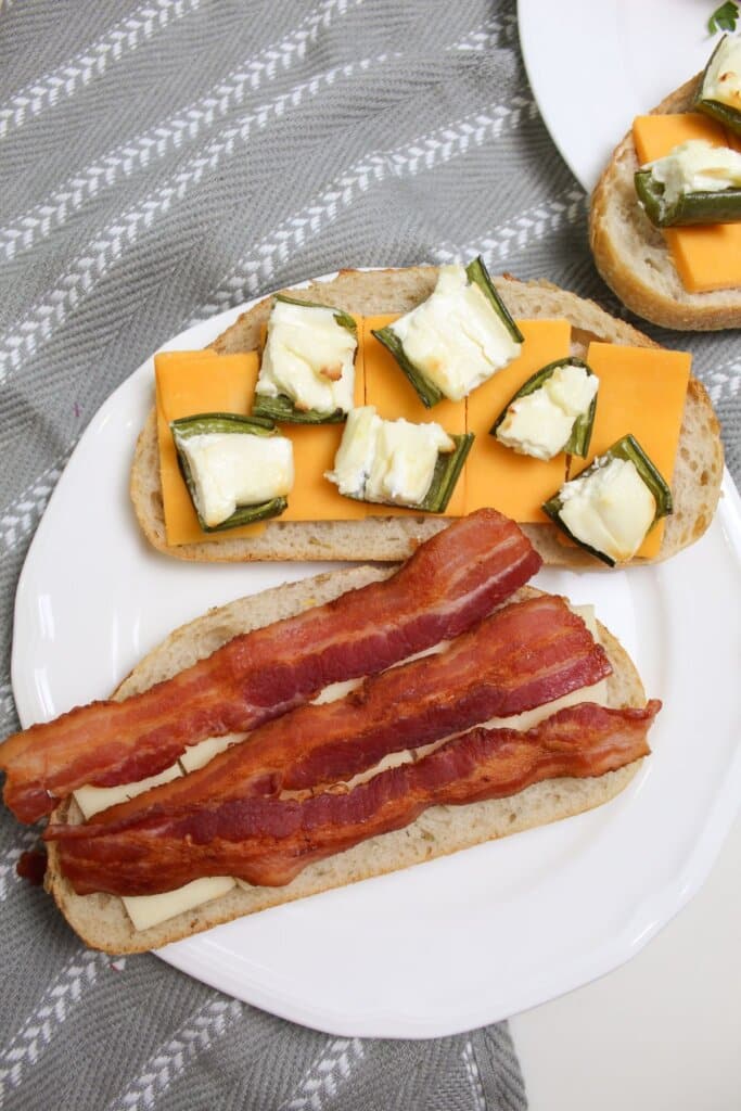 peppers, cheese, and bacon being placed on bread.