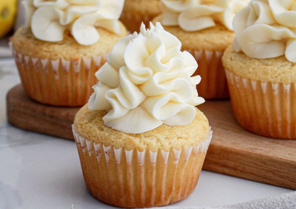 lemon cream cheese cupcakes on a wooden cutting board.